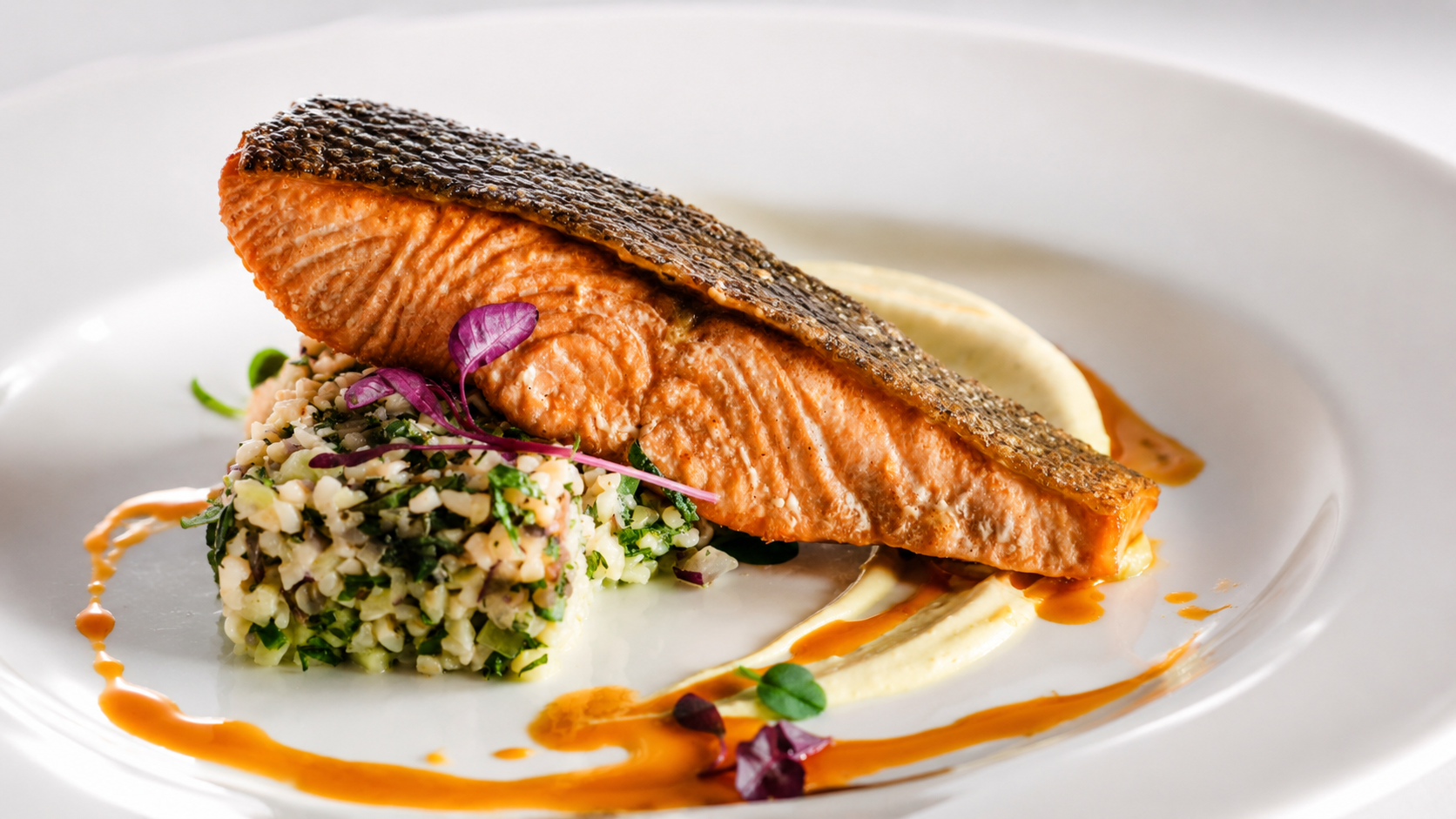 Seared salmon with herb rice, microgreens and citrus beurre blanc on an elegant white plate
